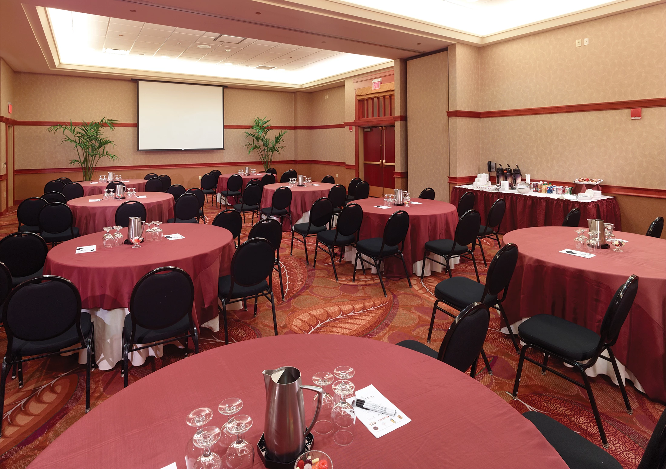 Meeting room set up with round tables and chairs facing a projector screen.